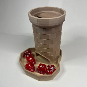 May include: A tan 3D-printed dice tower, designed to resemble a castle. The tower features a cylindrical body with a brick pattern and a tray at the base. Several red dice with white numbers are scattered around the base.