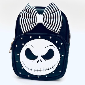 May include: Black faux leather backpack with a white and black striped bow and a white Jack Skellington face with rhinestones.