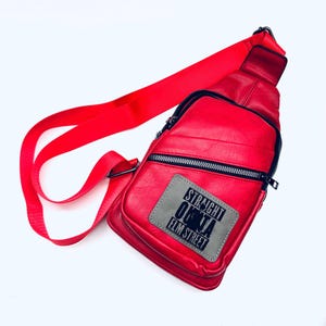 May include: Red leather crossbody bag with a black and gray patch that says "Straight Outta Elm Street".