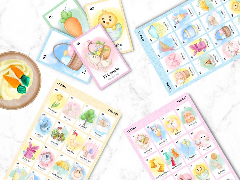 May include: A collection of colorful Loteria cards with Easter-themed illustrations, including bunnies, chicks, and eggs. The cards are arranged on a white marble surface, with some cards displaying the text "El Conejo" and "Loteria".