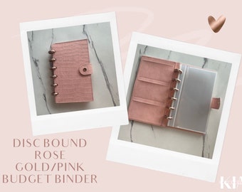 Peut inclure: Un classeur de budget rose à reliure à disques avec des accents dorés. Le classeur est fermé dans la première image et ouvert dans la deuxième image, montrant l'intérieur avec une poche en plastique transparente.