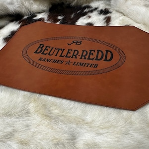 May include: A brown leather mat with a black oval logo that reads "Beutler-Redd Ranches Limited" with a star and a tick.
