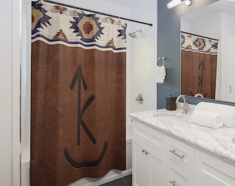 May include: A brown leather shower curtain with a black arrow and letter K design. The top of the curtain has a colorful geometric pattern in shades of red, blue, and white.