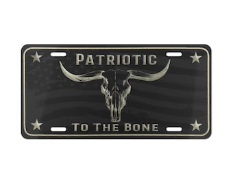 May include: Black and white license plate with a distressed American flag background. The text "PATRIOTIC TO THE BONE" is printed in white with a silver outline. A silver bull skull with horns is centered on the plate.