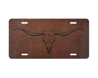 May include: Brown leather license plate with a black silhouette of a longhorn skull with horns.