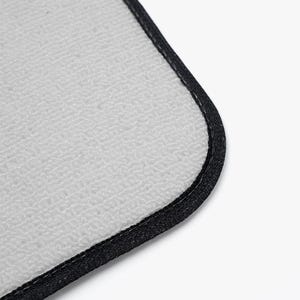 May include: A rectangular mouse pad with a light gray, textured fabric surface and a rounded corner. The edges of the mouse pad are finished with a thick, black stitched border that provides a clean and durable frame for the light gray center.