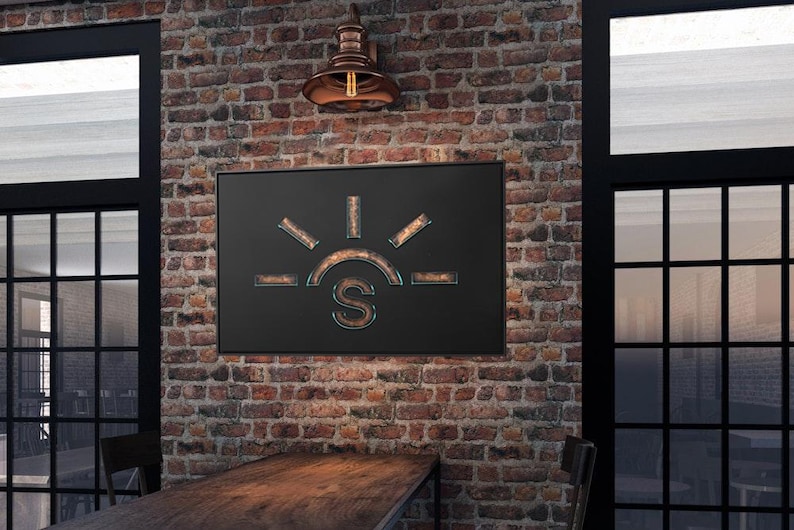 May include: A black metal sign with a stylised sun and the letter "S" in the centre. The sign is hanging on a brick wall with a copper light fixture above it.