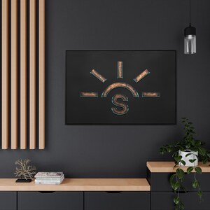 May include: A black and copper-coloured metal wall art piece depicting a stylised sun with the letter "S" in the centre. The sun has a copper-coloured outline and a turquoise-coloured interior.