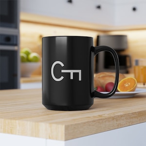 May include: A black ceramic coffee mug with a white key and the letter "C" printed on the side. The mug has a large handle.