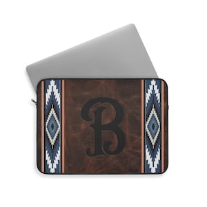 Puede incluir: Una funda para portátil de cuero marrón con un patrón geométrico azul y blanco en los lados. La letra "B" está en el centro de la funda en una fuente negra estilizada.