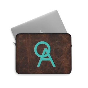 Könnte beinhalten: Braune Lederhülle für Laptops mit einem türkisfarbenen "OA"-Logo.