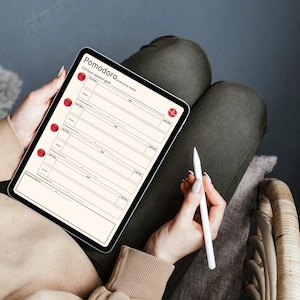 May include: A digital tablet displaying a Pomodoro session goal template. The tablet is held by a person, with a stylus resting nearby. The template features red circular accents and text.
