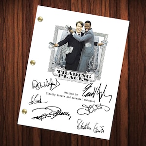 May include: A black and white photo of a movie script for the film "Trading Places". The script is signed by the writers Timothy Harris and Herschel Weingrod, as well as the actors Eddie Murphy, Dan Aykroyd, and Jamie Lee Curtis.