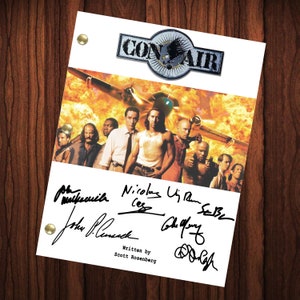 May include: A white script with the title "Con Air" in black and red letters. The script is signed by Nicolas Cage, John Cusack, Colm Meaney, and others. The background image is a fiery scene of a plane in flight.