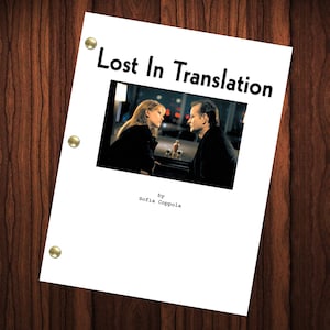 Könnte beinhalten: Ein weißes Blatt Papier mit dem Titel "Lost In Translation" und einem Filmbild mit zwei Personen. Der Text "by Sofia Coppola" steht darunter. Das Papier wird mit drei goldenen Heftklammern auf einem dunklen Holzgrund gehalten.