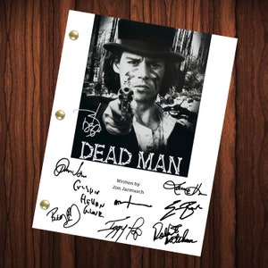 Peut inclure: Une photo en noir et blanc d'un homme portant un chapeau et tenant une arme à feu. La photo est sur une feuille de papier blanche avec le titre "Dead Man" et plusieurs signatures en dessous. Le texte "Written by Jim Jarmusch" est également sur le papier.