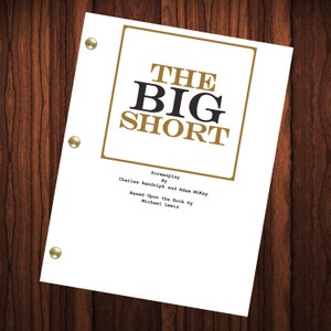 May include: A white script cover with a gold border and the title "THE BIG SHORT" in black and gold lettering. The text "Screenplay By Charles Randolph and Adam McKay Based Upon the Book by Michael Lewis" is printed in black below the title.