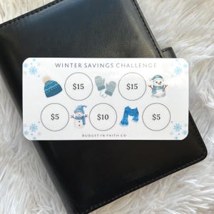 May include: A white Winter Savings Challenge card with blue snowflake accents, a blue hat, mittens, scarf, and snowman illustrations. The card has circles with dollar amounts: $5, $10, and $15. The text "WINTER SAVINGS CHALLENGE" is at the top.