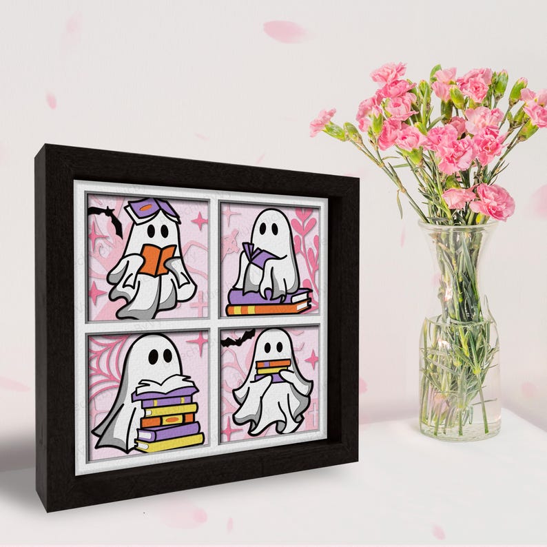 May include: A framed print with four illustrations of ghosts reading books. Each ghost is white with a purple outline and is sitting on or holding a stack of books. The background is pink with a floral pattern.