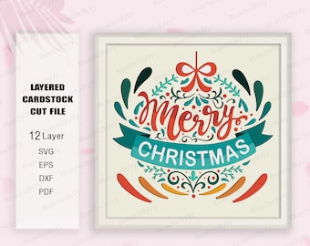 Könnte beinhalten: Eine mehrschichtige Karton-Schneidedatei mit einem festlichen Weihnachtsornament mit dem Text "Merry Christmas" in einer farbenfrohen, verspielten Schriftart. Das Ornament ist mit grünen, roten und blauen floralen Elementen verziert.