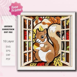 May include: A layered cardstock cut file featuring a brown squirrel holding an acorn, set within a window frame. The scene includes autumn leaves in shades of red, yellow, and orange. The image includes the text "Free Frame" and "Layered Cardstock Cut File".
