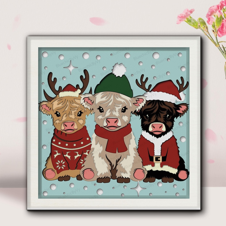 May include: A framed print featuring three Highland cows dressed for the holidays. One cow wears a reindeer antler hat and a red sweater. Another wears a green hat and red scarf. The third cow is in a Santa suit.