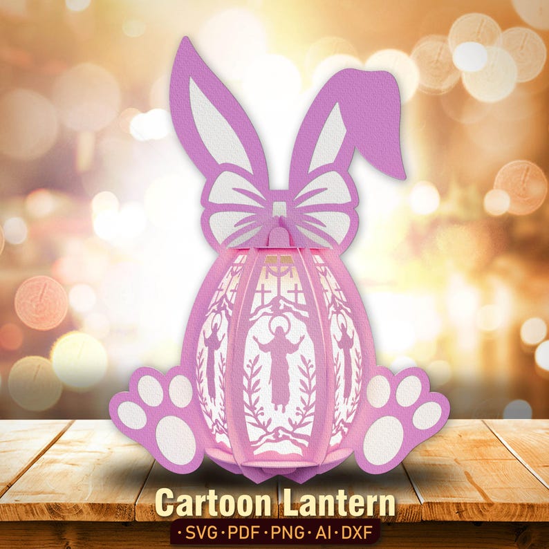 Pu&ograve; includere: Una lanterna di Pasqua a forma di coniglio rosa e bianco con una croce e figure religiose all'interno. La lanterna ha la forma di un uovo e un fiocco in cima. Il testo "Cartoon Lantern" &egrave; stampato sotto la lanterna.
