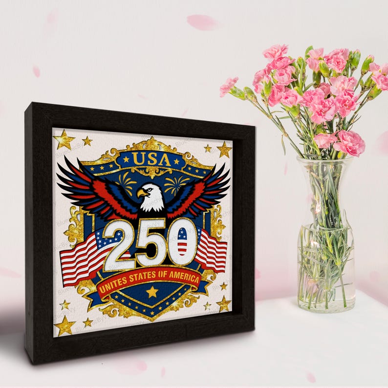 Puede incluir: Una impresi&oacute;n enmarcada que celebra el 250 aniversario de los Estados Unidos de Am&eacute;rica. La obra de arte presenta un &aacute;guila, banderas americanas y el texto "USA 250". El marco negro rodea la impresi&oacute;n, que se encuentra cerca de un jarr&oacute;n con flores rosas.
