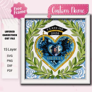 May include: A layered cardstock cut file in a white frame, featuring a heart-shaped design with a graduation theme. The design includes the text "CLASS OF 2026" and "OLIVIA", with a photo inside. The frame is surrounded by green leaves and blue floral accents.