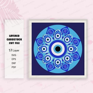 Pode incluir: Um design de arquivo de corte de cartão em camadas que apresenta um mandala de olho mau azul e branco. O design é composto por 17 camadas e inclui arquivos SVG, EPS, DXF e PDF.