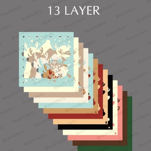 May include: A stack of 13 layered paper cutouts with a winter theme. The top cutout features a light blue background with reindeer and snowflakes. The other layers are various colors, including beige, brown, and red.