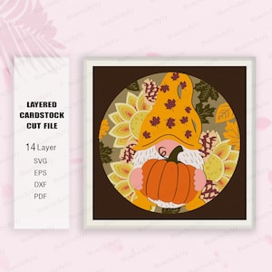 May include: A layered cardstock cut file design featuring a gnome holding a pumpkin. The gnome is wearing a brown hat with orange and red accents. The background is a circle with a brown, orange, and yellow floral pattern.