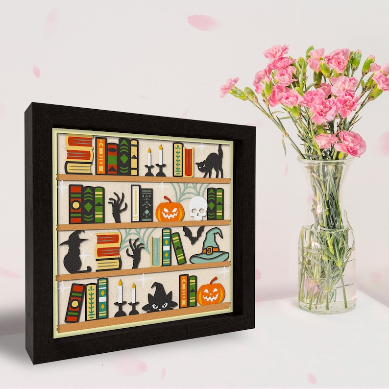 May include: A framed illustration of a bookshelf filled with books, pumpkins, candles, bats, a witch's hat, and a black cat. The bookshelf is decorated with a spooky Halloween theme.