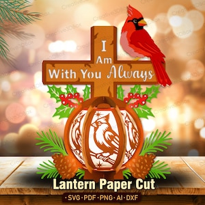 May include: A decorative paper cut design featuring a brown cross with the text I Am With You Always, topped by a red cardinal bird. Below the cross is a spherical lantern with cardinal illustrations, accented by green pine needles and red berries.