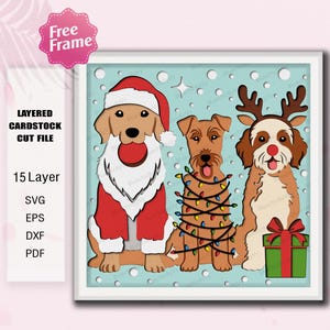 Könnte beinhalten: Mehrschichtige Karton-Schnittdatei mit drei Hunden in festlicher Kleidung. Ein Hund ist als Weihnachtsmann verkleidet, ein anderer ist mit Lichterketten umwickelt, und der dritte trägt Rentiergeweih. Der Hintergrund ist hellblau mit weißen Schneeflocken.