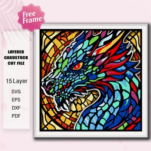 Op de afbeelding: Een kleurrijk gelaagd kartonnen snijbestand met een drakenkop. De draak is afgebeeld in tinten blauw, groen, rood en geel, met een glas-in-lood effect. De afbeelding bevat de tekst "Free Frame" en bestandstype-opties.