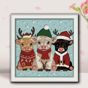 May include: A framed print featuring three Highland cows dressed for Christmas. One cow wears a red sweater and reindeer antlers, another a green hat and scarf, and the third a Santa suit and hat. The background is light blue.