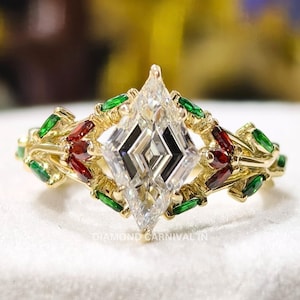 May include: A gold ring with a central diamond-shaped, multi-faceted clear stone. The ring is adorned with red and green gemstones, set in a decorative pattern. The ring is displayed on a white surface.