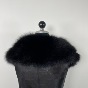 May include: A black fur collar on a black dress form.