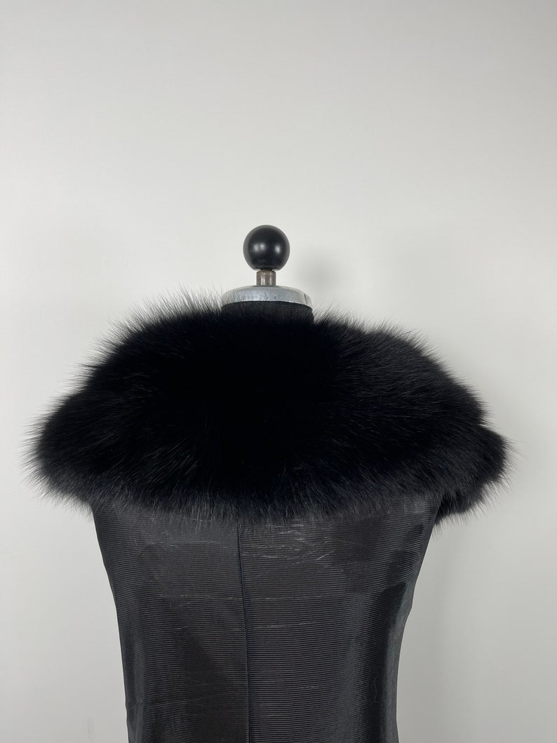 May include: A black fur collar on a black dress form.