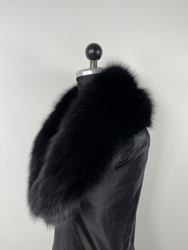 May include: A black fur collar, worn on a black mannequin. The collar is thick and fluffy, with a soft, luxurious texture.