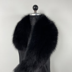 May include: A black fur collar on a mannequin. The collar is made of soft, fluffy fur and is designed to be worn around the neck.