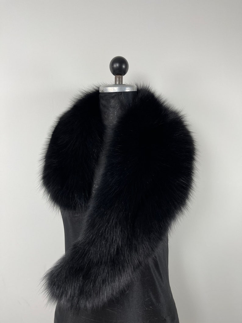 May include: A black fur collar on a mannequin. The collar is made of soft, fluffy fur and is designed to be worn around the neck.