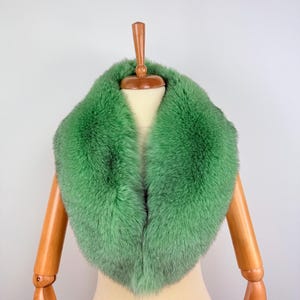 Puede incluir: Un cuello de piel verde en un maniquí. El cuello está hecho de piel suave y esponjosa y tiene un diseño clásico y elegante.