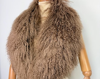 May include: A brown, fluffy fur collar with a curly texture. The collar is displayed on a mannequin with wooden arms and a wooden neck post. The fur appears to be a light brown color and is densely packed, creating a voluminous look.