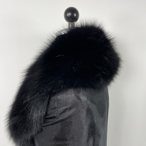 May include: A black fur collar with a soft, fluffy texture. The collar is displayed on a black mannequin.