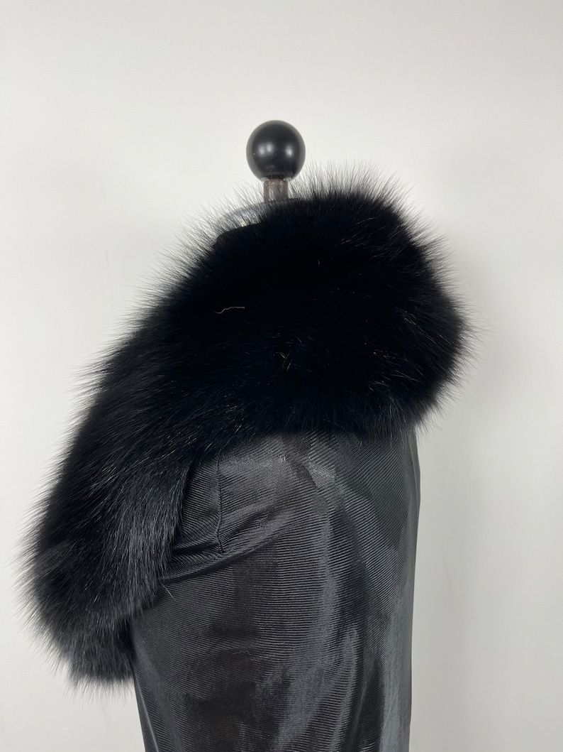 May include: A black fur collar with a soft, fluffy texture. The collar is displayed on a black mannequin.