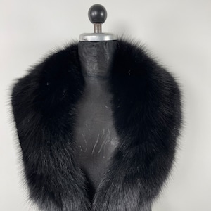 May include: A black faux fur collar for a coat or jacket. The collar is made of soft, fluffy fur and has a classic design.
