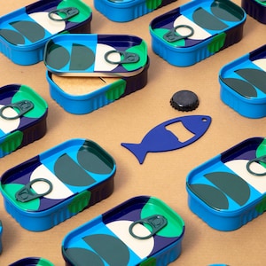 Könnte beinhalten: Draufsicht auf mehrere blau-grüne Sardinenbüchsen mit geometrischem Design. Eine Dose ist geöffnet und zeigt den Inhalt. Ein blauer, fischförmiger Flaschenöffner und ein schwarzer Kronkorken sind ebenfalls zu sehen.