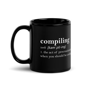 May include: Black coffee mug with white text that reads "compiling" and a definition of the word. The definition is "verb [kəm'pīl-ing] 1. the act of procrastinating when you should be coding."